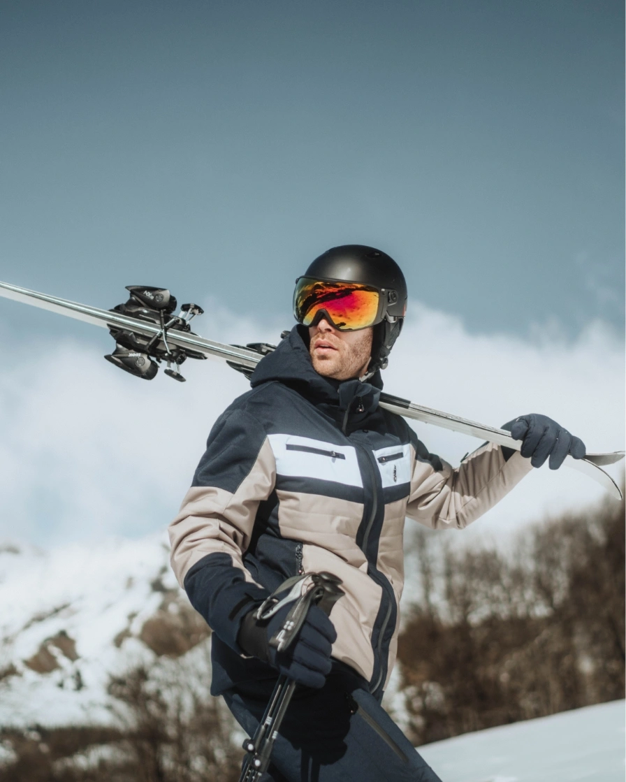 Man in skiwear carring skis